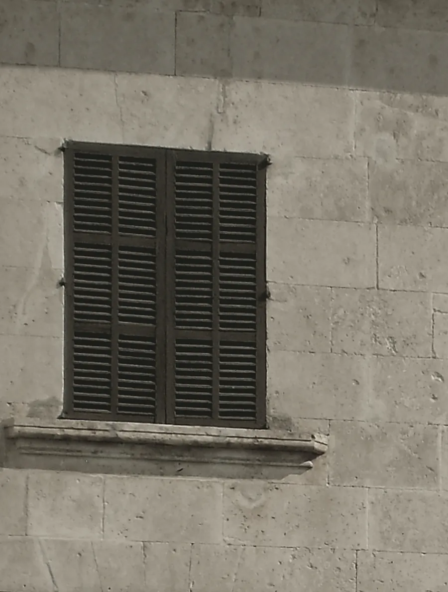 Fassade aus Marès-Sandstein mit gemeißeltem Fenstersturz und dunkelgrünem Fensterladen